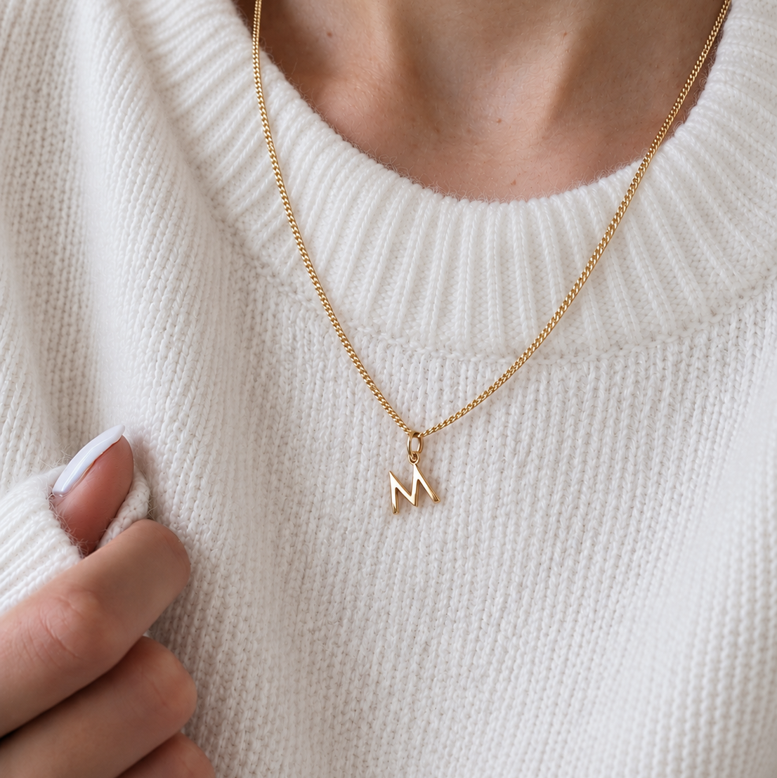 Zarte Buchstaben Kette in gold getragen von Frau. Die Goldkett mit dem Buchstaben M ist ein persönliches Geschenk für deine Freundin oder Ehepartnerin. Mit dem Anfangsbuchstaben an der Kette trägt sie dich immer nah am Herzen. Handgefertigt in Berlin in Gold und Silber und auch in 333 Go.d und 585 Gold.