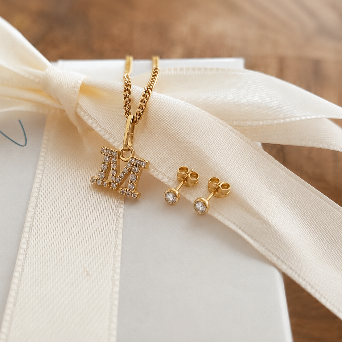 Das EDITH Geschenkset kombiniert die Goldkette mit dem Buchstaben M mit passenden Ohrsteckern – ein perfektes Geschenk für die Liebste.