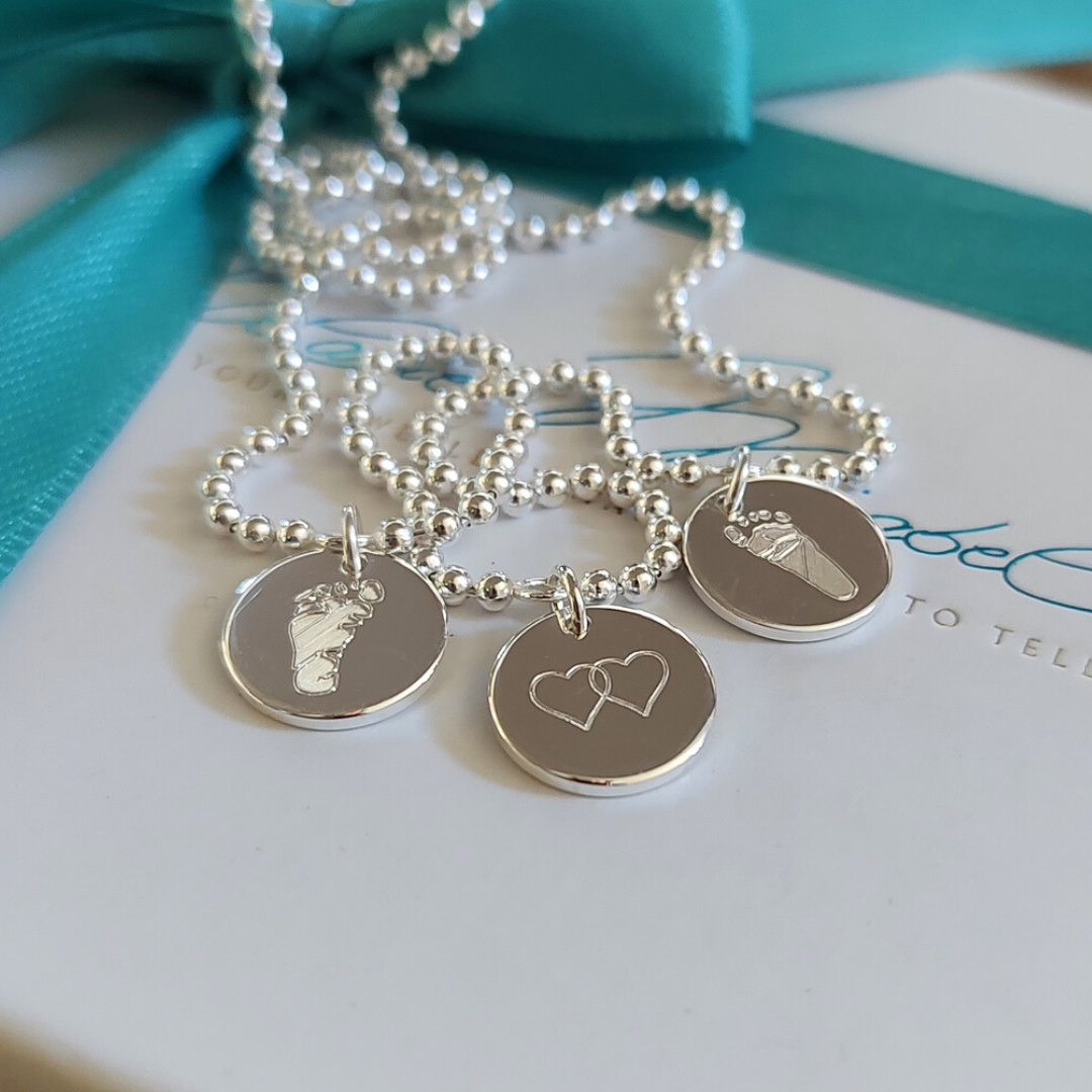 nahaufnahme der namenskette für mütter mit drei Plättchen und Babyfußabdruck-Gravur – ein liebevolles Erinnerungsstück für frischgebackene Mamas. Perfektes Geschenk für Mütter mit 1, 2 oder 3 KInder