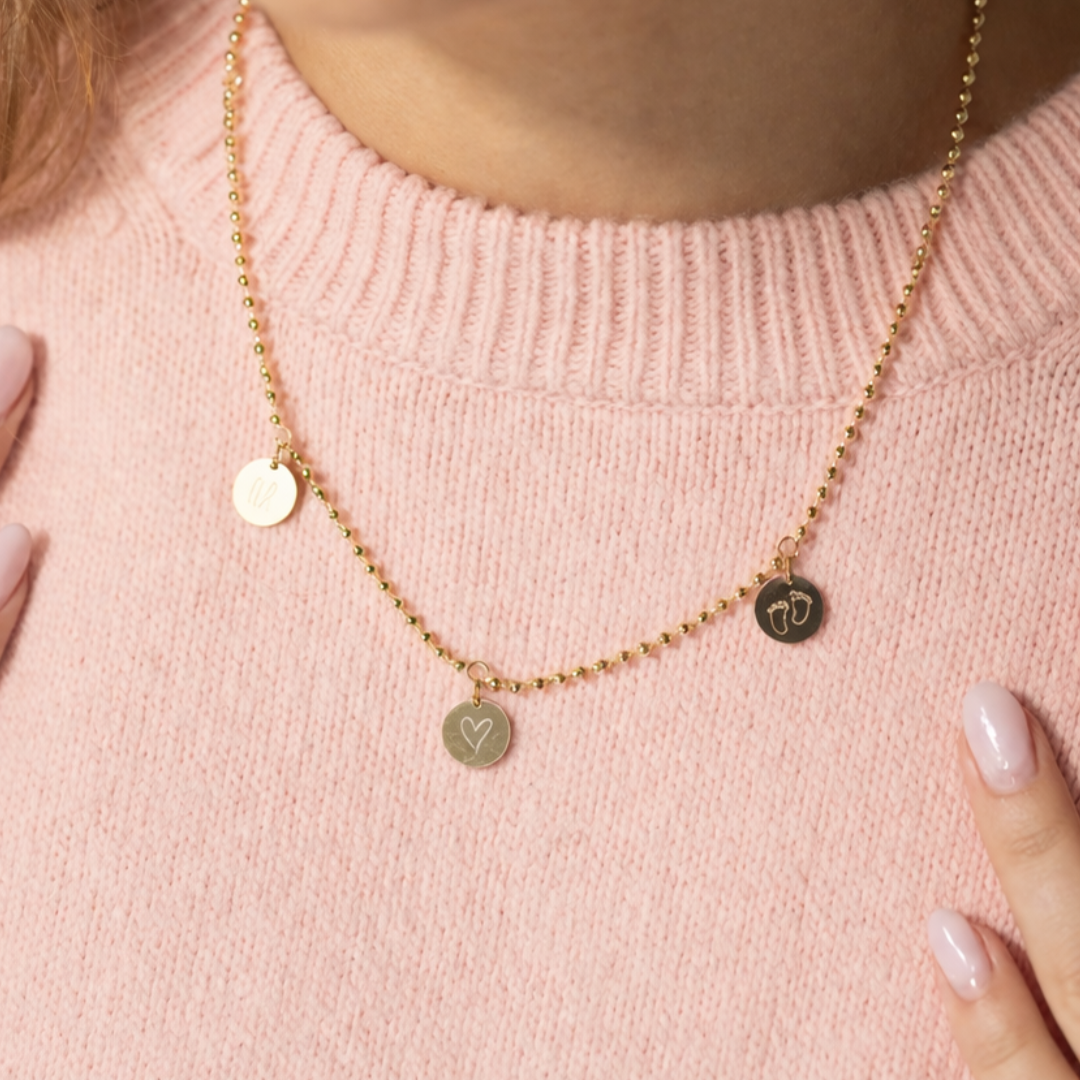 Die Familienkette DREAM TEAM in Gold mit drei kleinen Gravur-Anhängern, liebevoll graviert mit den Namen der Kinder. Ein persönliches Geschenk für Mama zur Geburt, zum Muttertag oder Geburtstag – handgefertigt in unserer Berliner Goldschmiede.