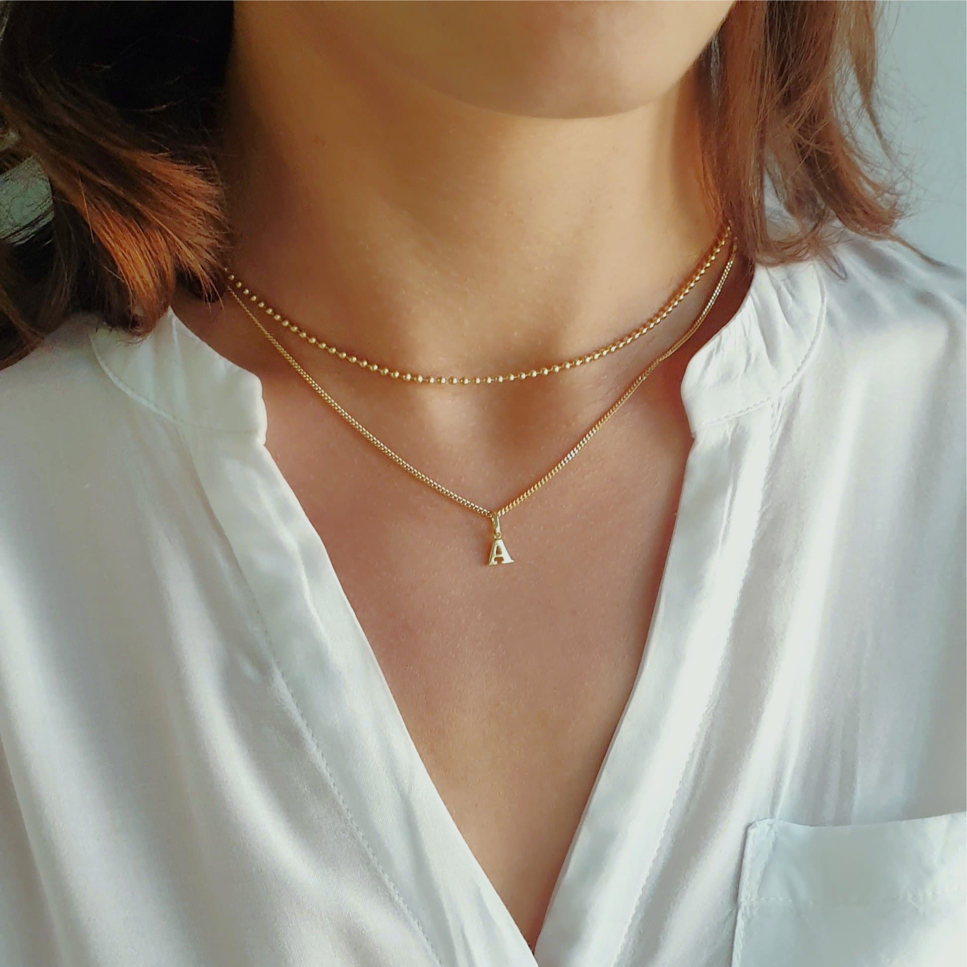 Buchstaben Kette mit Initialen Anhänger aus Echtgold getragen an einer feinen Goldkette. Ein persönliches Geschenk zum Jahrestag, Geburtstag oder als Zeichen der Verbundenheit, dass das Herz jeder Mama, Freundin und Ehefrau garantiert höher schlagen lässt. In Weissgold und Gelbgold wahlweise 333, 585 und 750 Gold angefertigt in Berlin. 